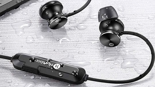 Black waterproof earbuds with a neckband and control panel shown on a wet surface, with water droplets on the earbuds and cable.