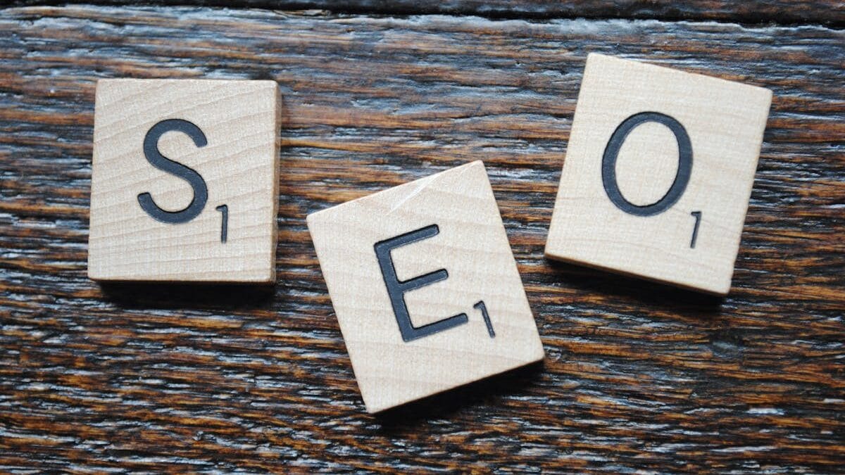 Wooden Scrabble tiles spell "SEO" on a wooden surface.