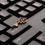 A vintage brass key placed on a black computer keyboard, resting between the Enter and Shift keys.