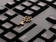 A vintage brass key placed on a black computer keyboard, resting between the Enter and Shift keys.