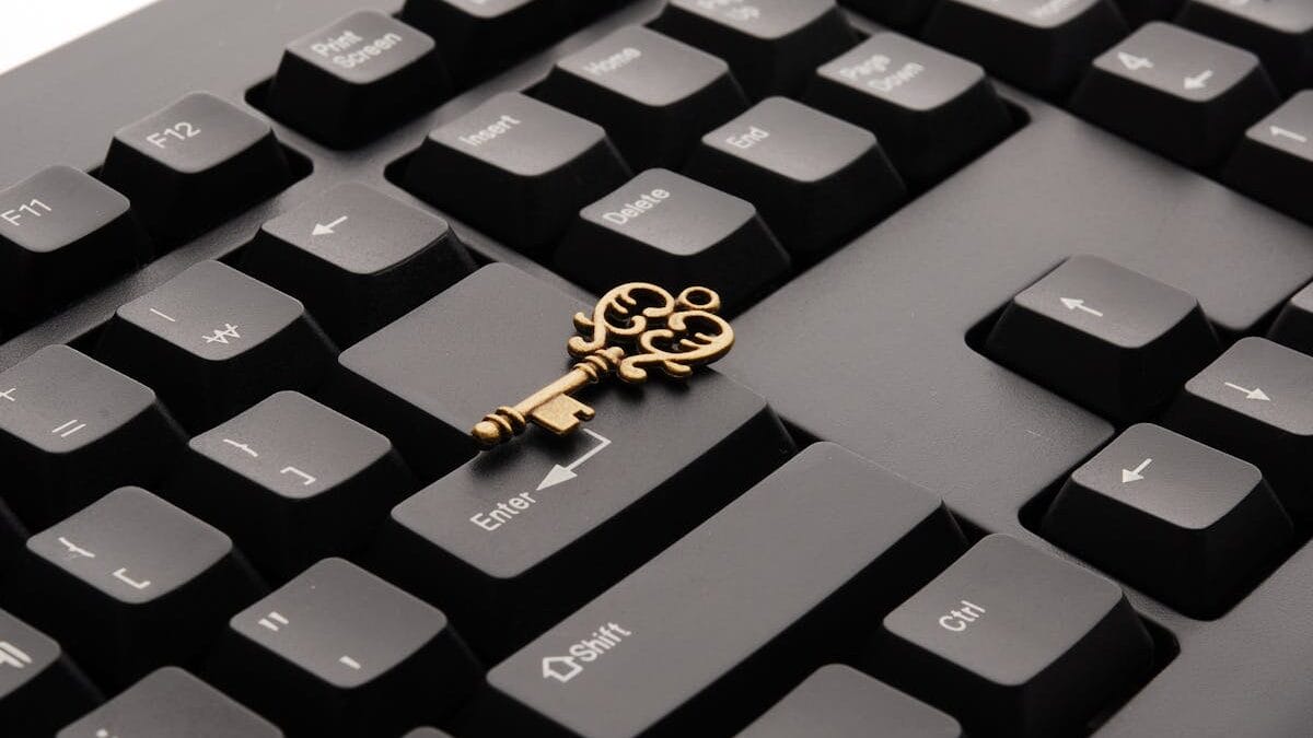 A vintage brass key placed on a black computer keyboard, resting between the Enter and Shift keys.