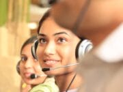 Three people wearing headsets, focused on a task, with one person prominently in the foreground.