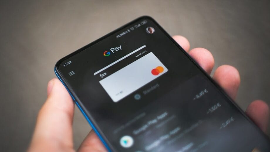 A hand holding a smartphone displaying the Google Pay app with a Mastercard on screen.