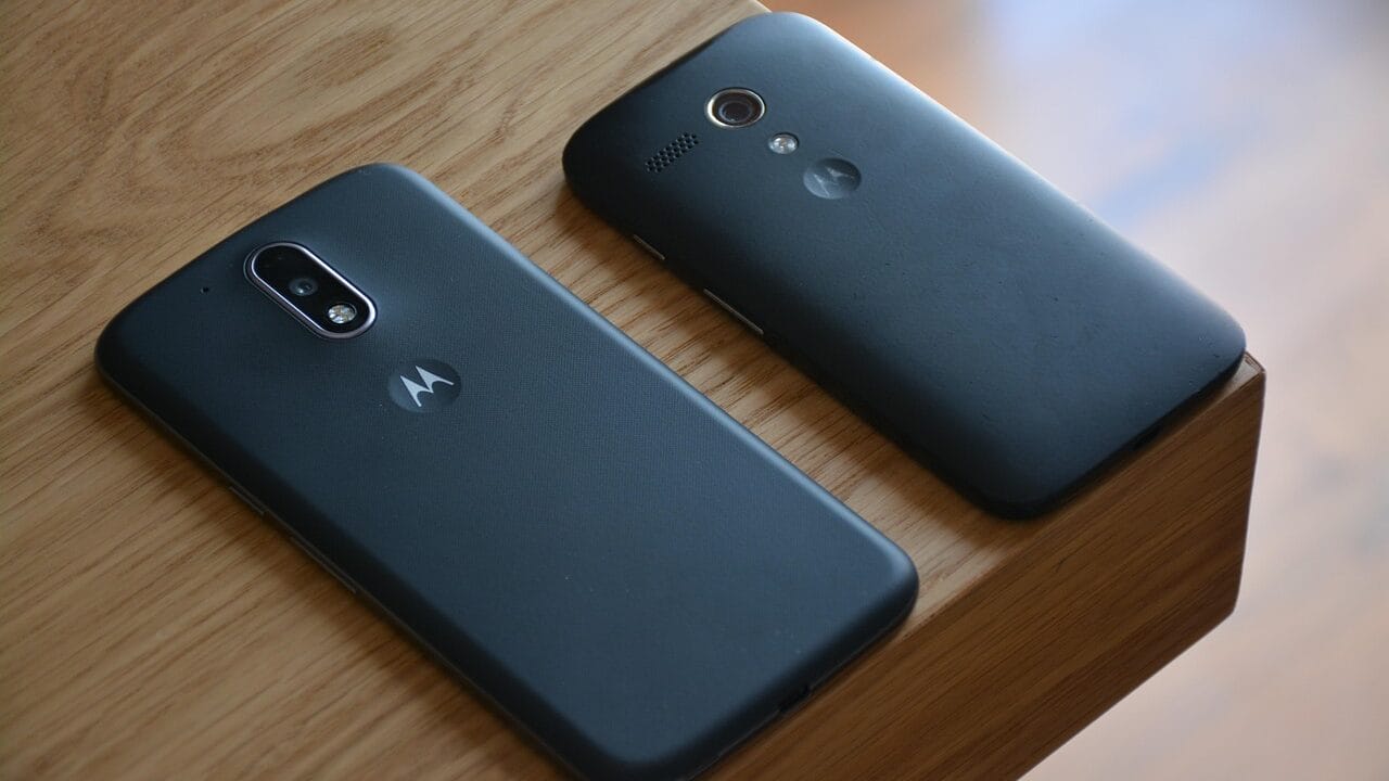 Two black Motorola smartphones are placed side by side on a wooden surface.