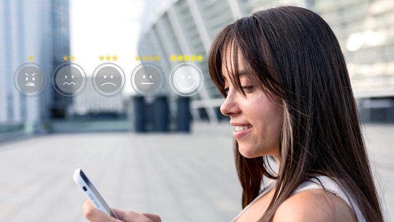 Woman outdoors looking at her phone, with a row of five emoticon rating icons and star ratings superimposed in front of her.