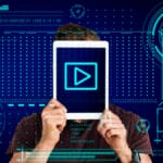 A person holds a tablet in front of their face displaying a play button, with digital graphic elements in the background.