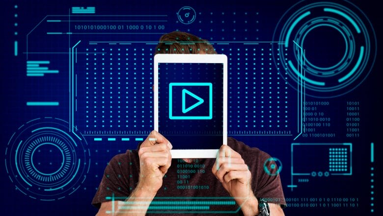 A person holds a tablet in front of their face displaying a play button, with digital graphic elements in the background.