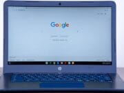 An HP laptop displaying the Google search homepage on its screen, placed on a flat surface.