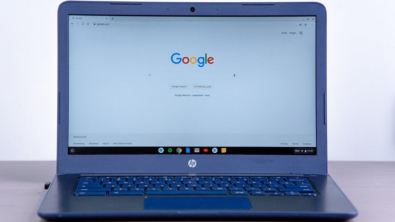 An HP laptop displaying the Google search homepage on its screen, placed on a flat surface.