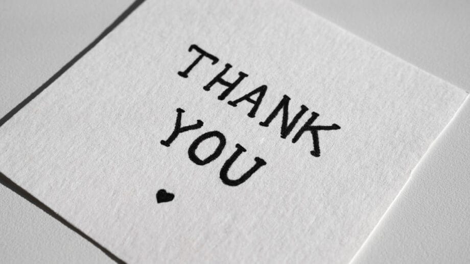 A white card with the words THANK YOU and a small black heart printed below the text.