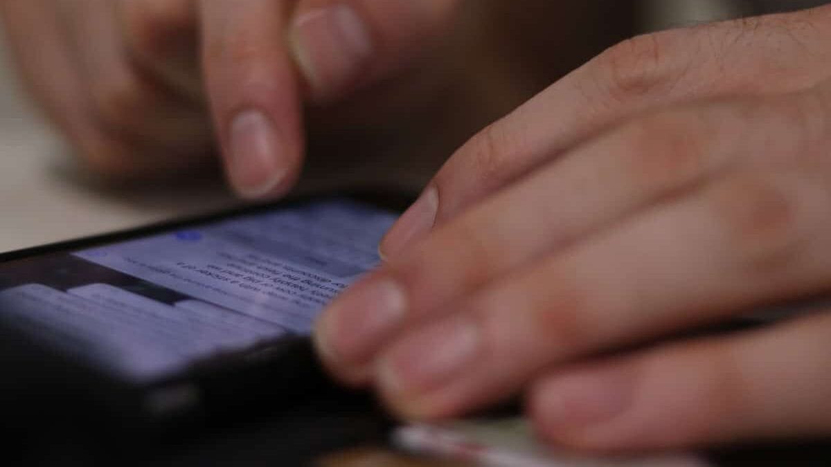 A person uses their fingers to scroll through messages on a smartphone screen.