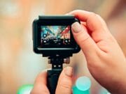 Close-up of hands holding a camera, capturing a busy city street scene visible on the camera’s display screen.