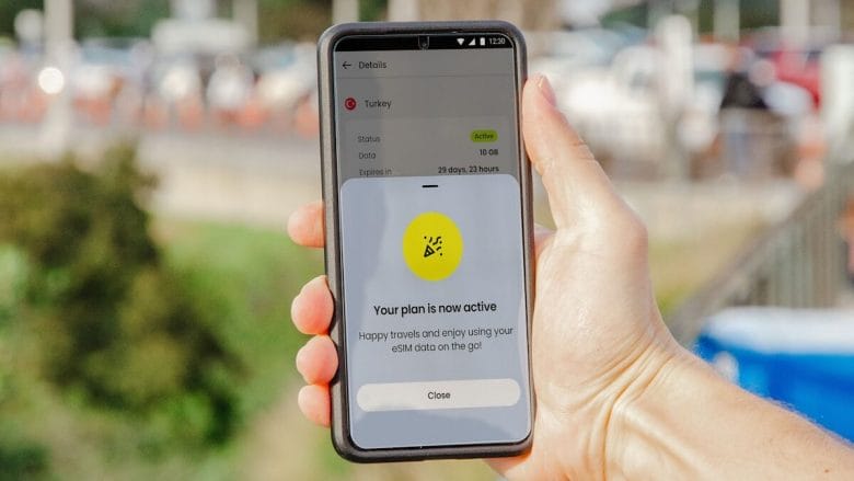 A hand holds a smartphone displaying a screen that confirms an active mobile data plan with a 65MB allowance.