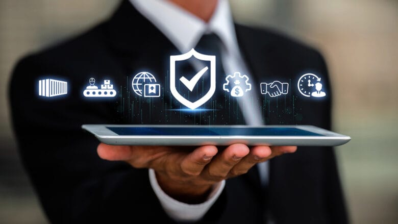A person in a suit holds a tablet displaying floating digital icons representing security, logistics, and business processes.