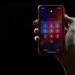 A hand holds a smartphone displaying a passcode entry screen against a black background.