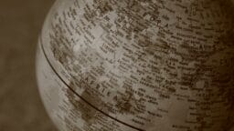 Sepia-toned close-up of a globe showing parts of Europe, Africa, and Asia, with country names visible.