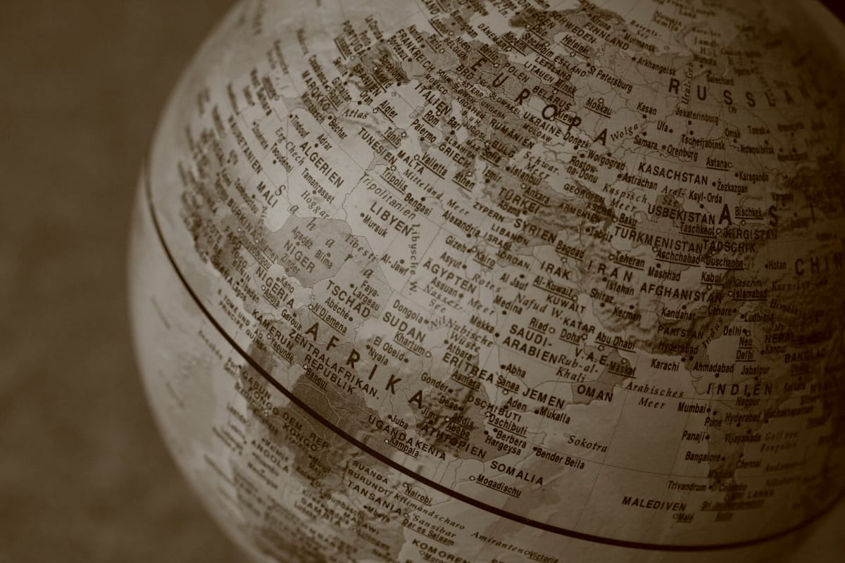 Sepia-toned close-up of a globe showing parts of Europe, Africa, and Asia, with country names visible.
