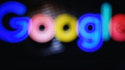 Blurry image of the Google logo with bright blue, red, yellow, and green colors on a dark background.
