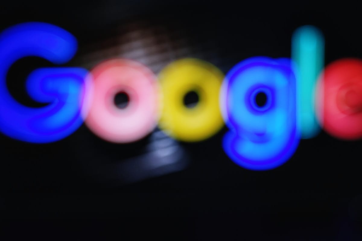 Blurry image of the Google logo with bright blue, red, yellow, and green colors on a dark background.