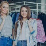Two smiling women holding shopping bags.