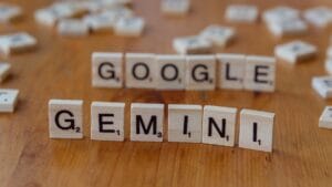 Wooden letter tiles on a table spell out GOOGLE in the back row and GEMINI in the front row.