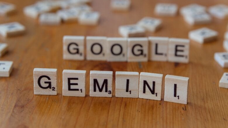Wooden letter tiles on a table spell out GOOGLE in the back row and GEMINI in the front row.