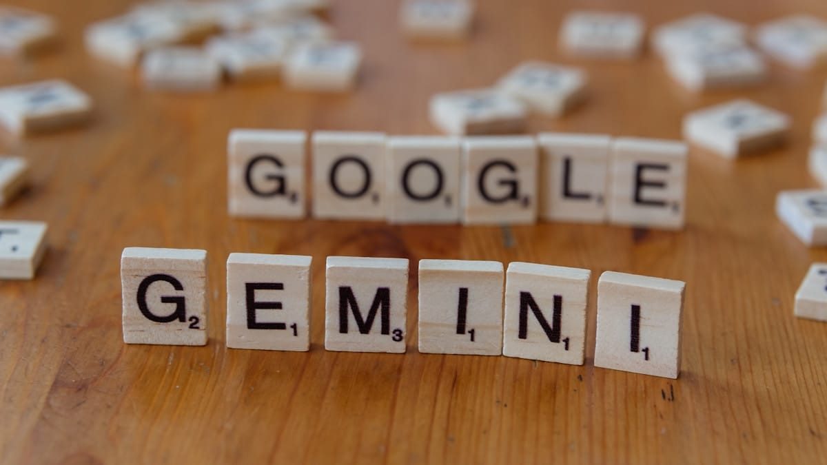 Wooden letter tiles on a table spell out GOOGLE in the back row and GEMINI in the front row.