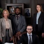 A diverse group of business professionals posing in an office, showcasing teamwork and leadership.
