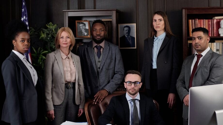 A diverse group of business professionals posing in an office, showcasing teamwork and leadership.