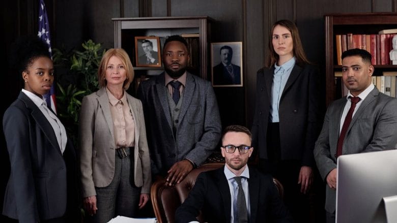 A diverse group of business professionals posing in an office, showcasing teamwork and leadership.