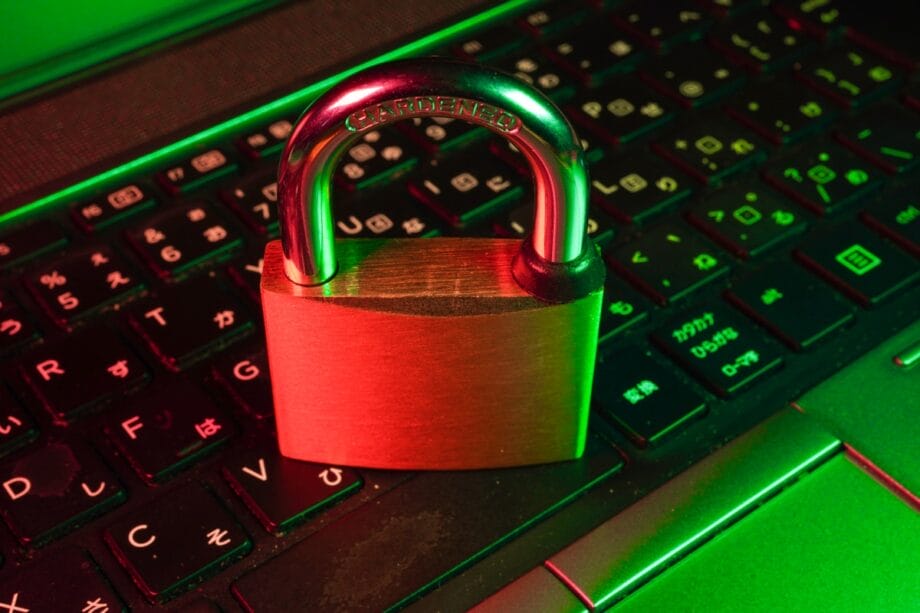 A brass padlock sits on a laptop keyboard illuminated by red and green lights, symbolizing cybersecurity or data protection.