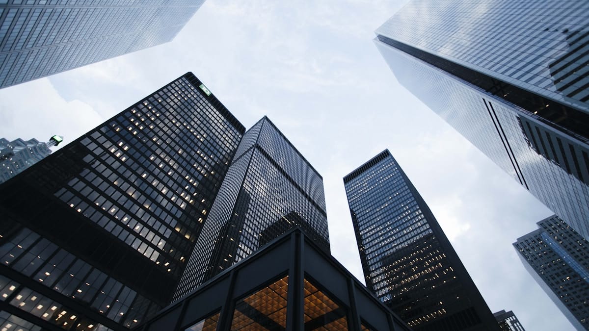 Tall modern skyscrapers with glass exteriors photographed from below against a cloudy sky.