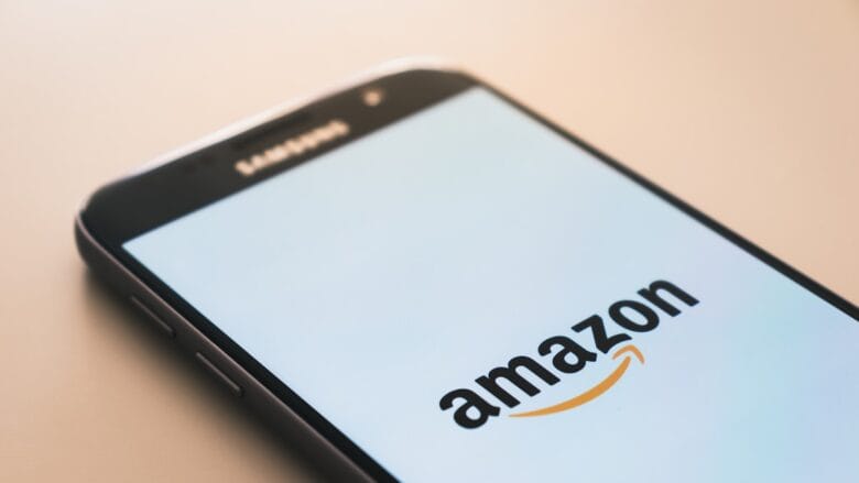 A smartphone displays the Amazon logo on its screen, with the top edge of the phone labeled Samsung.
