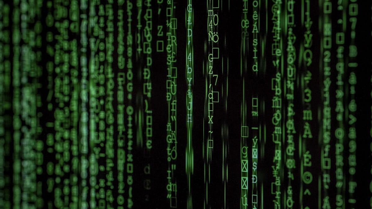 Green code-like symbols cascade down a black screen, resembling a digital matrix or computer code rain effect.