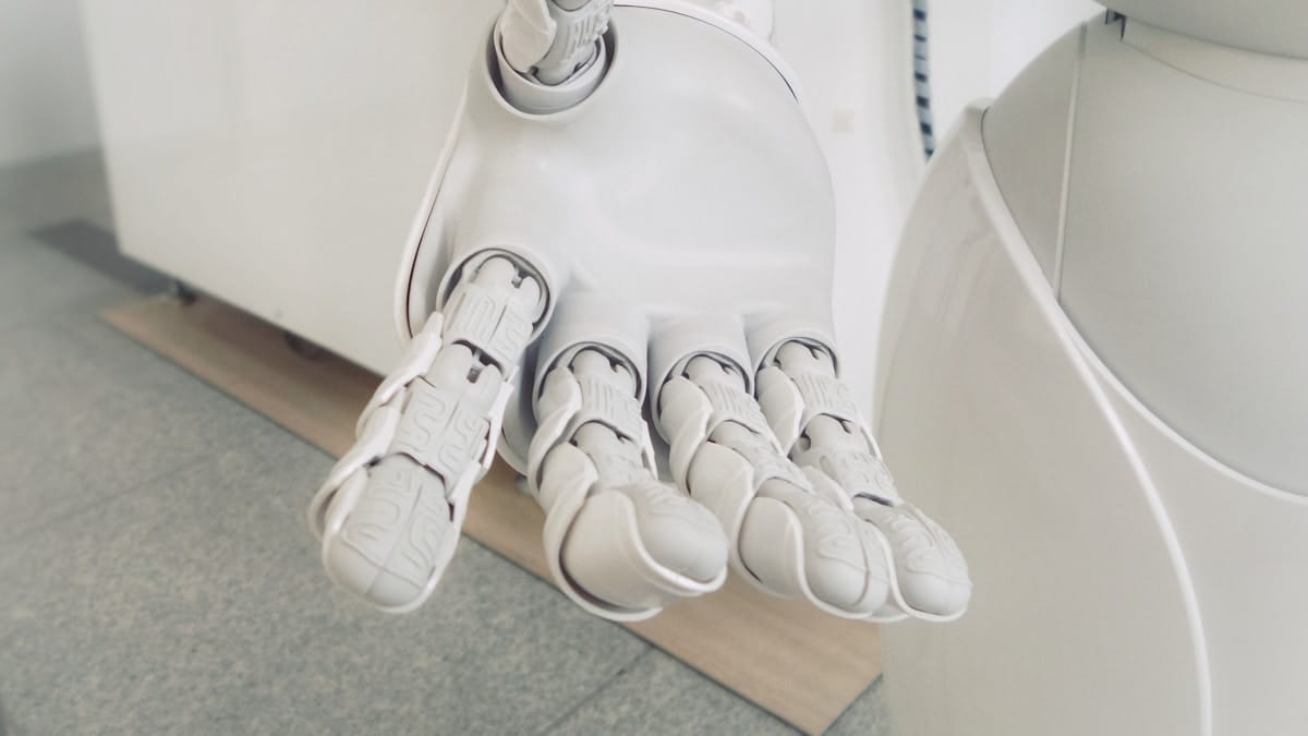 A close-up of an outstretched robotic hand and forearm, displaying detailed mechanical joints and fingers.