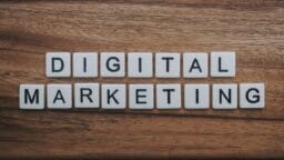 Letter tiles arranged on a wooden surface spell out Digital Marketing in two rows.