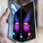 A hand holds an open foldable smartphone displaying a butterfly image across both screens.