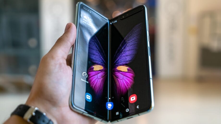 A hand holds an open foldable smartphone displaying a butterfly image across both screens.