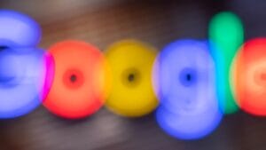 Blurred image of the Google logo with indistinct, colorful letters on a dark background.