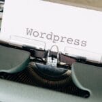 A close-up of a typewriter with a paper sheet displaying the word Wordpress typed on it.