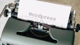 A close-up of a typewriter with a paper sheet displaying the word Wordpress typed on it.