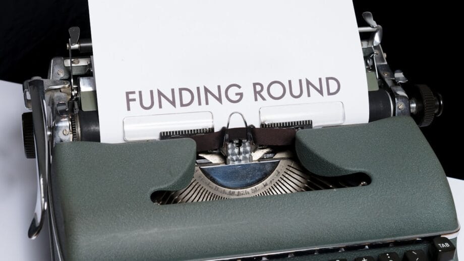 A typewriter with a paper displaying the words FUNDING ROUND written in large letters.