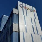 A modern office building with the Google logo on the upper corner, set against a clear blue sky.