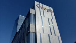 A modern office building with the Google logo on the upper corner, set against a clear blue sky.