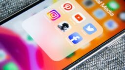 Close-up of a smartphone screen showing social media app icons including Pinterest, YouTube, Instagram, Clubhouse, Twitter, and Facebook.