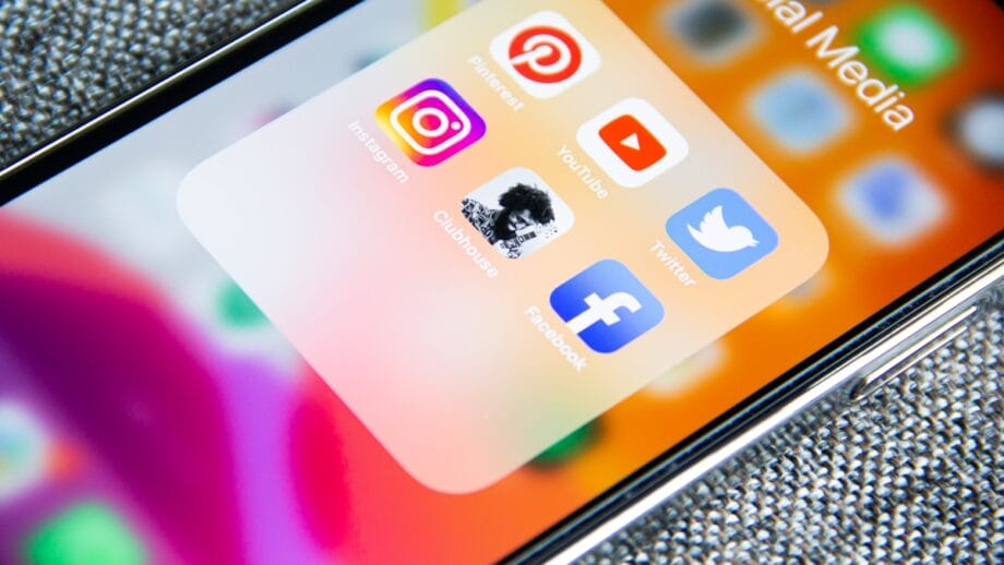 Close-up of a smartphone screen showing social media app icons including Pinterest, YouTube, Instagram, Clubhouse, Twitter, and Facebook.