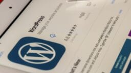 Close-up of the WordPress app download page on a tablet, showing its logo, rating, and a blue cloud icon.
