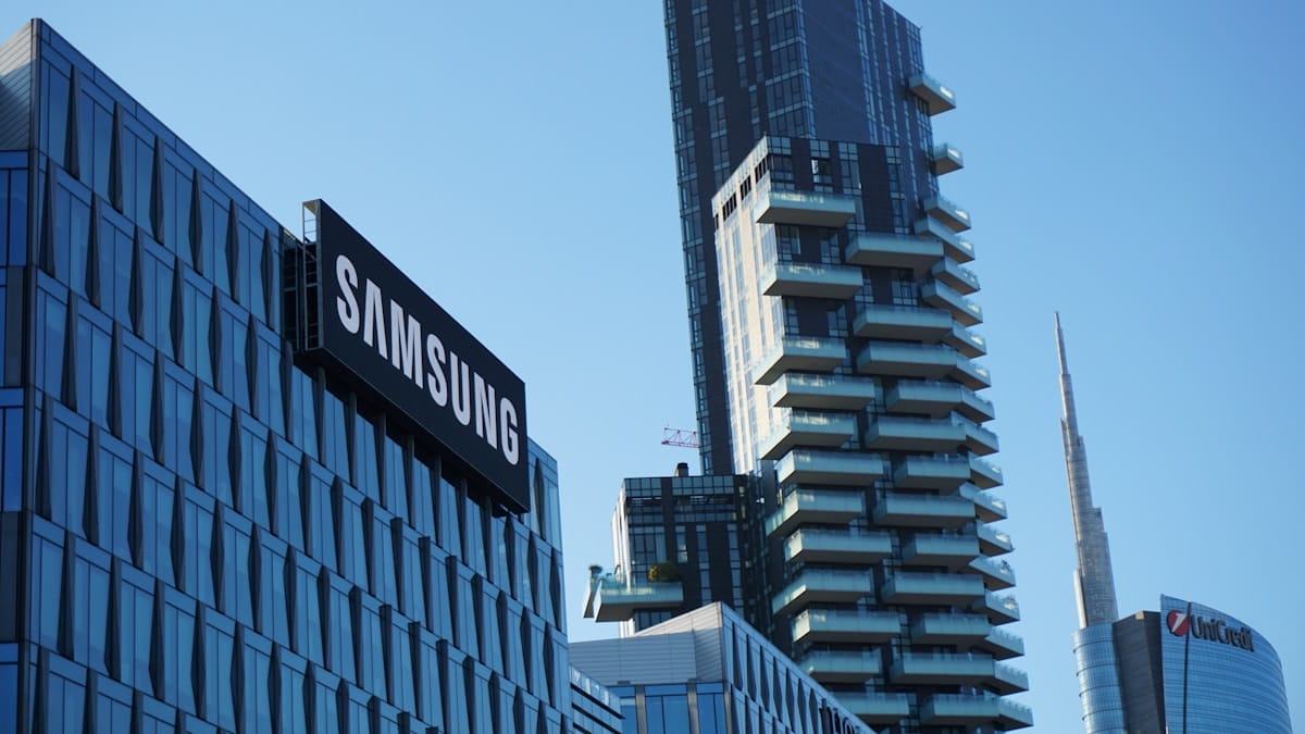 Modern cityscape with a Samsung building in the foreground and high-rise towers in the background under a clear blue sky.