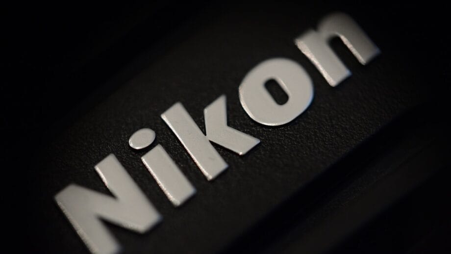 Close-up of a Nikon logo in silver letters on a textured black surface.