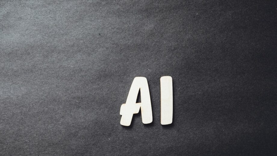 Wooden letters spelling AI on a dark textured background with space on the left side.